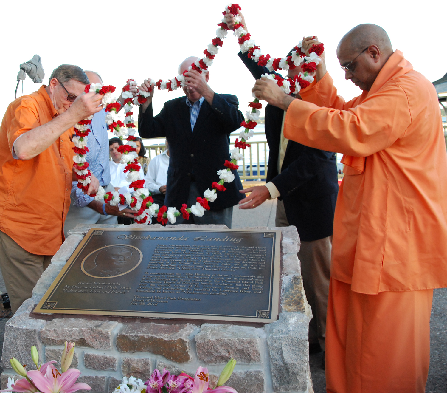 Swami Yuktatmananda and others laying flowers on memorial.