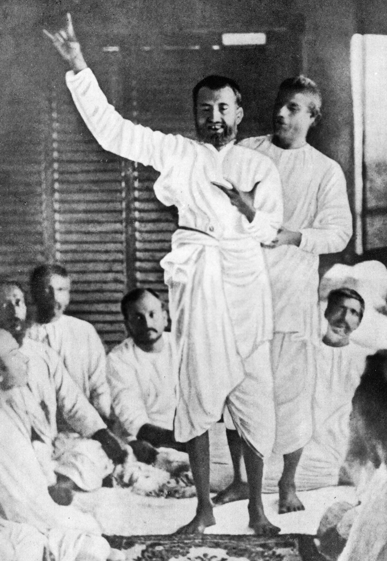 Black and white photo of Sri Ramakrishna preaching to others.